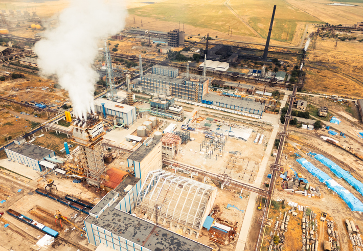 Aerial view of Rustavi Azot factory complex in Georgia showing production buildings, storage tanks, tall chimneys emitting smoke, and extensive industrial infrastructure